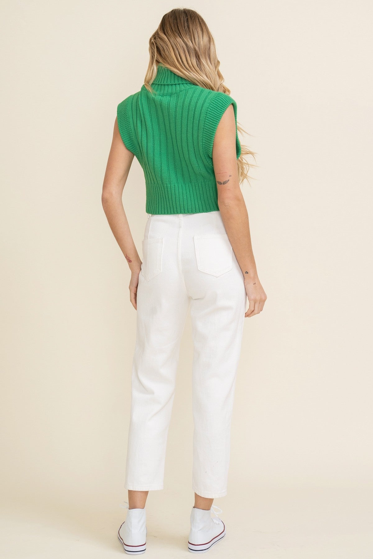 Cropped knit sleeveless sweater in green features a loose turtleneck and oversized fit. Back view.