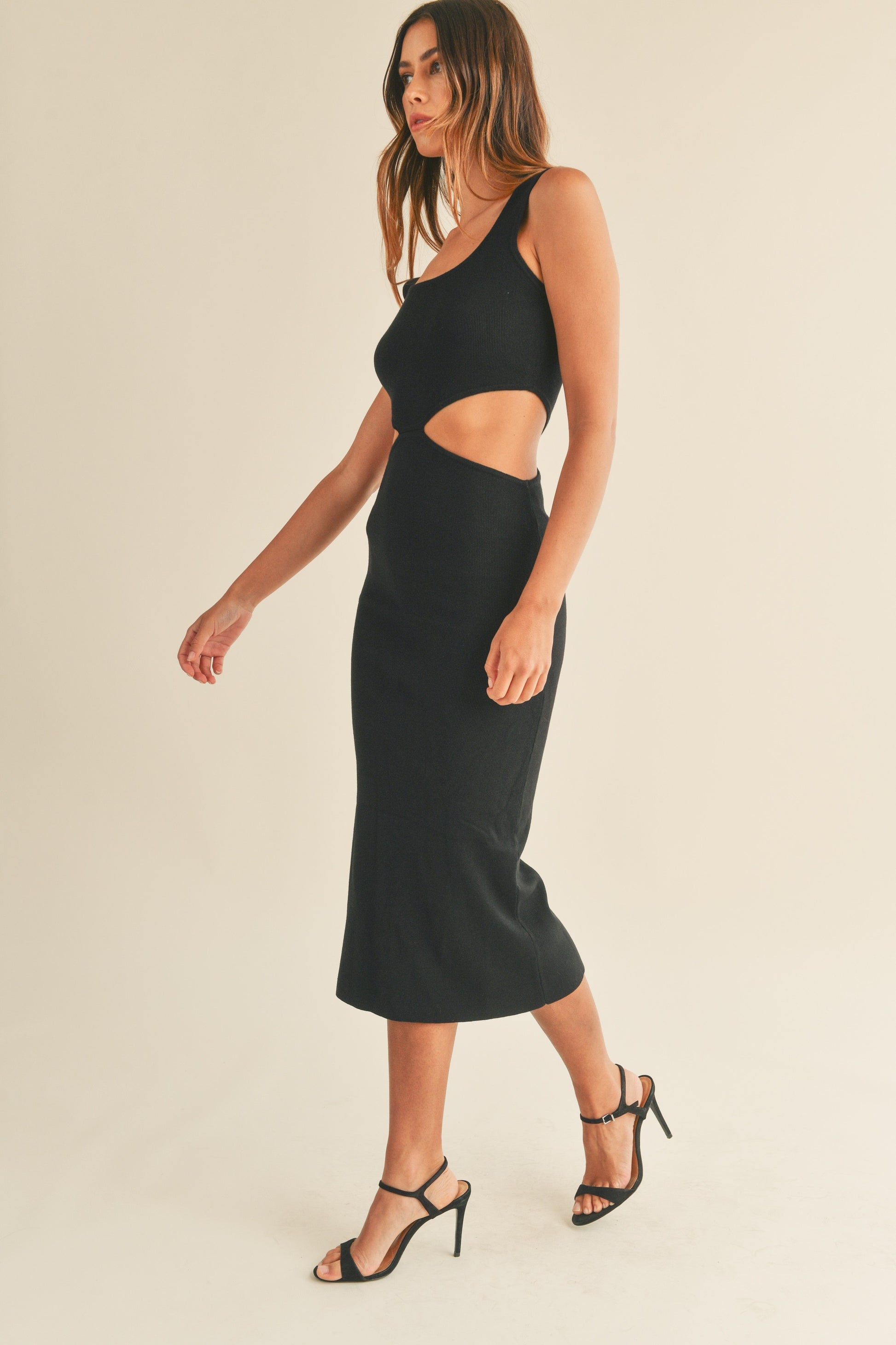 Knit sleeveless midi dress in black features side cut outs and a tank-style top. Side view.