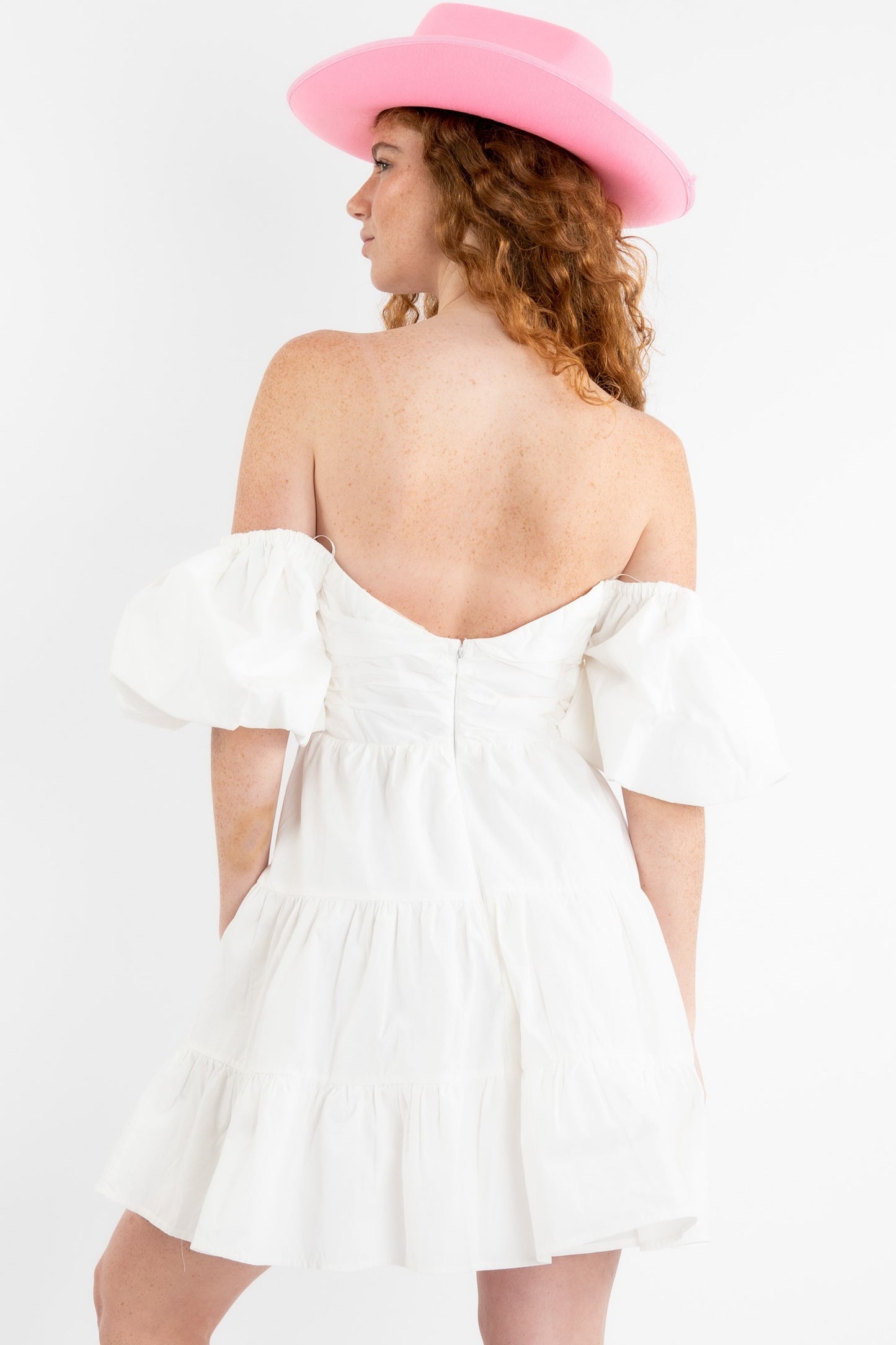 Poplin mini dress in off white featuring a v-trim front and puff sleeves that can be worn on or off the shoulder. Back view.