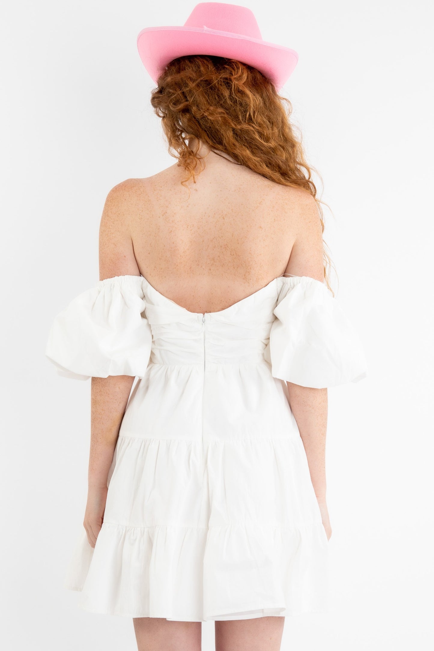 Poplin mini dress in off white featuring a v-trim front and puff sleeves that can be worn on or off the shoulder. Back view.