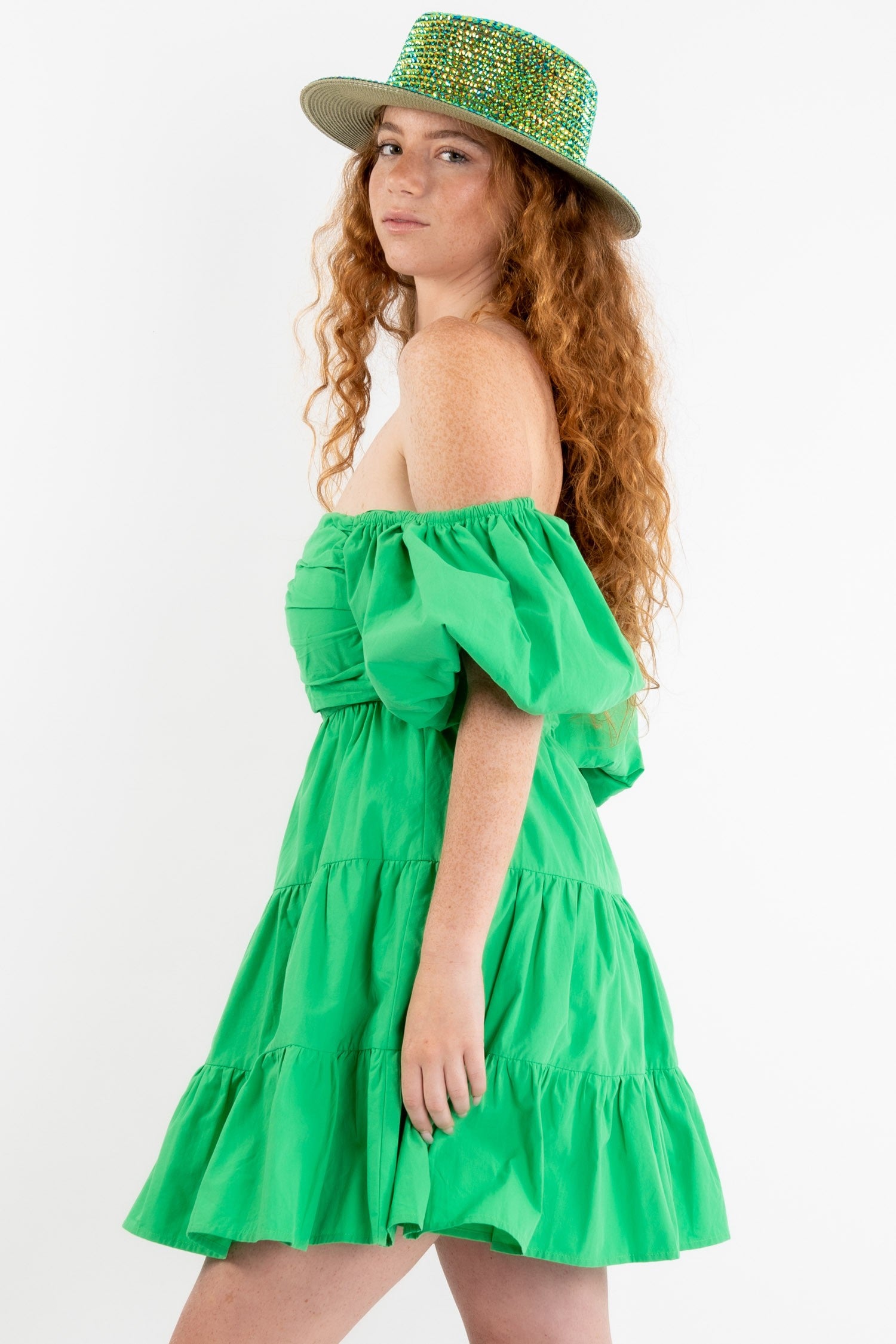 Poplin mini dress in green featuring a v-trim front and puff sleeves that can be worn on or off the shoulder. Side view.