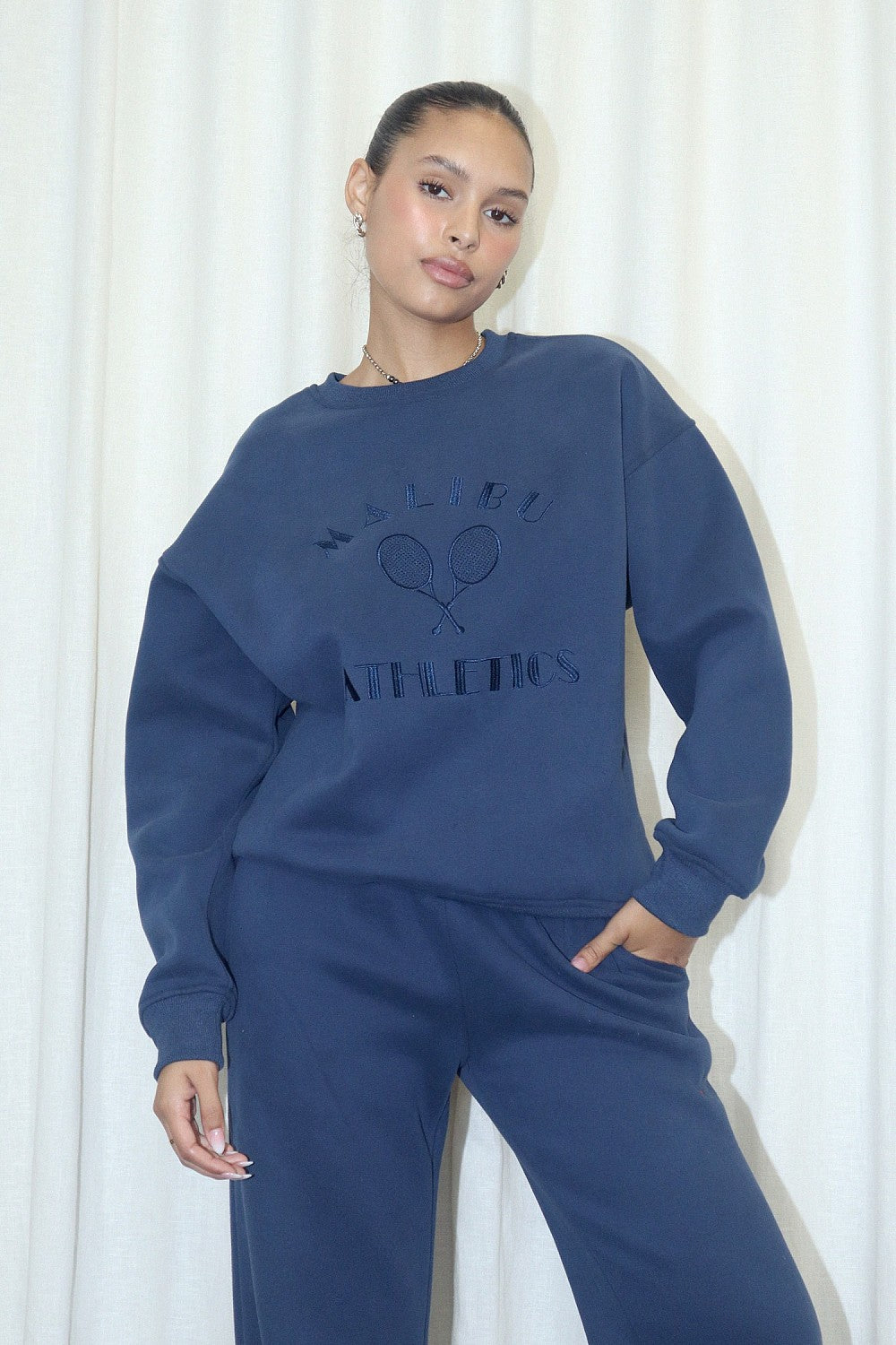 Oversized fleece-lined crewneck sweatshirt in navy.  Embroidered on the front with "Malibu Athletics" and rackets.  Front view.