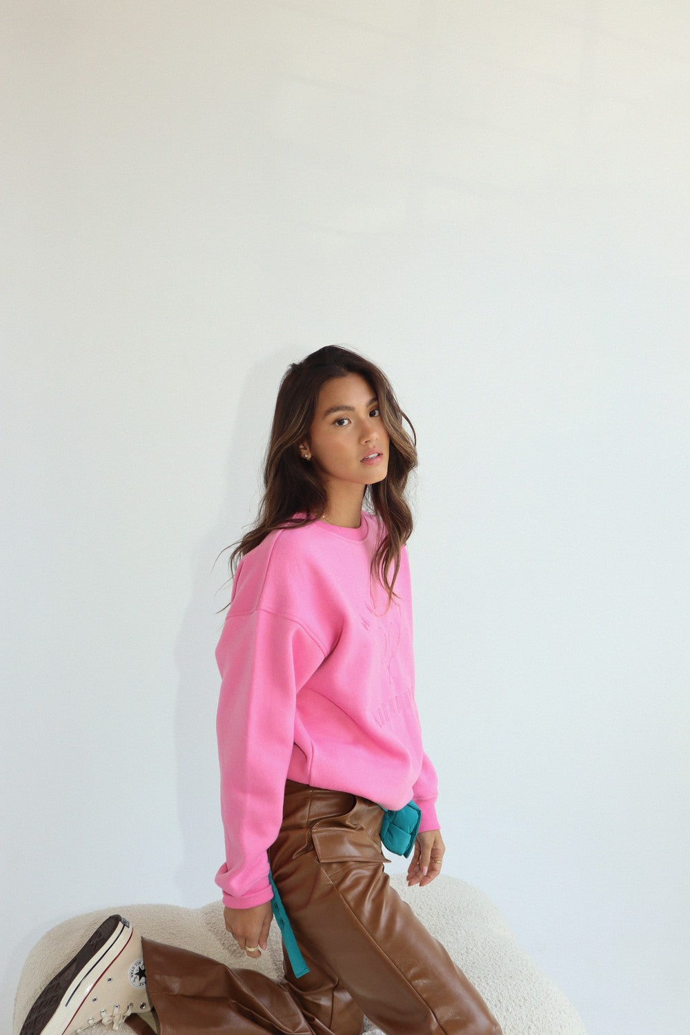 Oversized fleece-lined crewneck sweatshirt in pink.  Embroidered on the front with "Malibu Athletics" and rackets.  Side view.