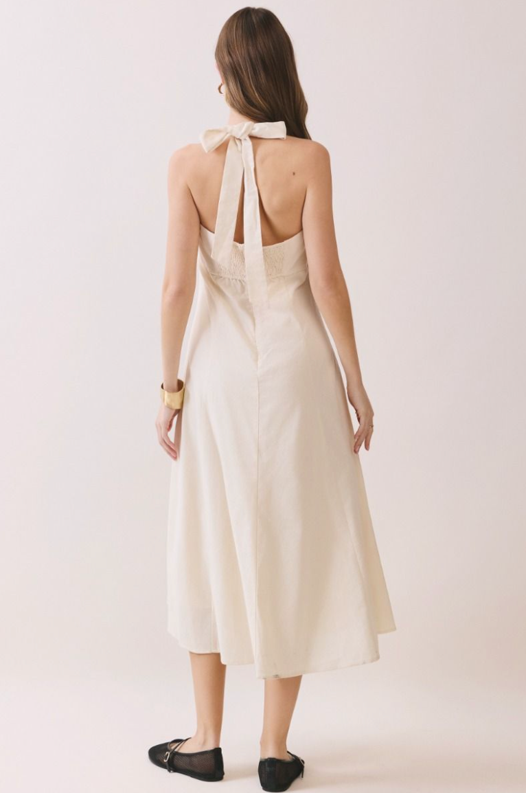 Woman standing in long creme dress, ack view