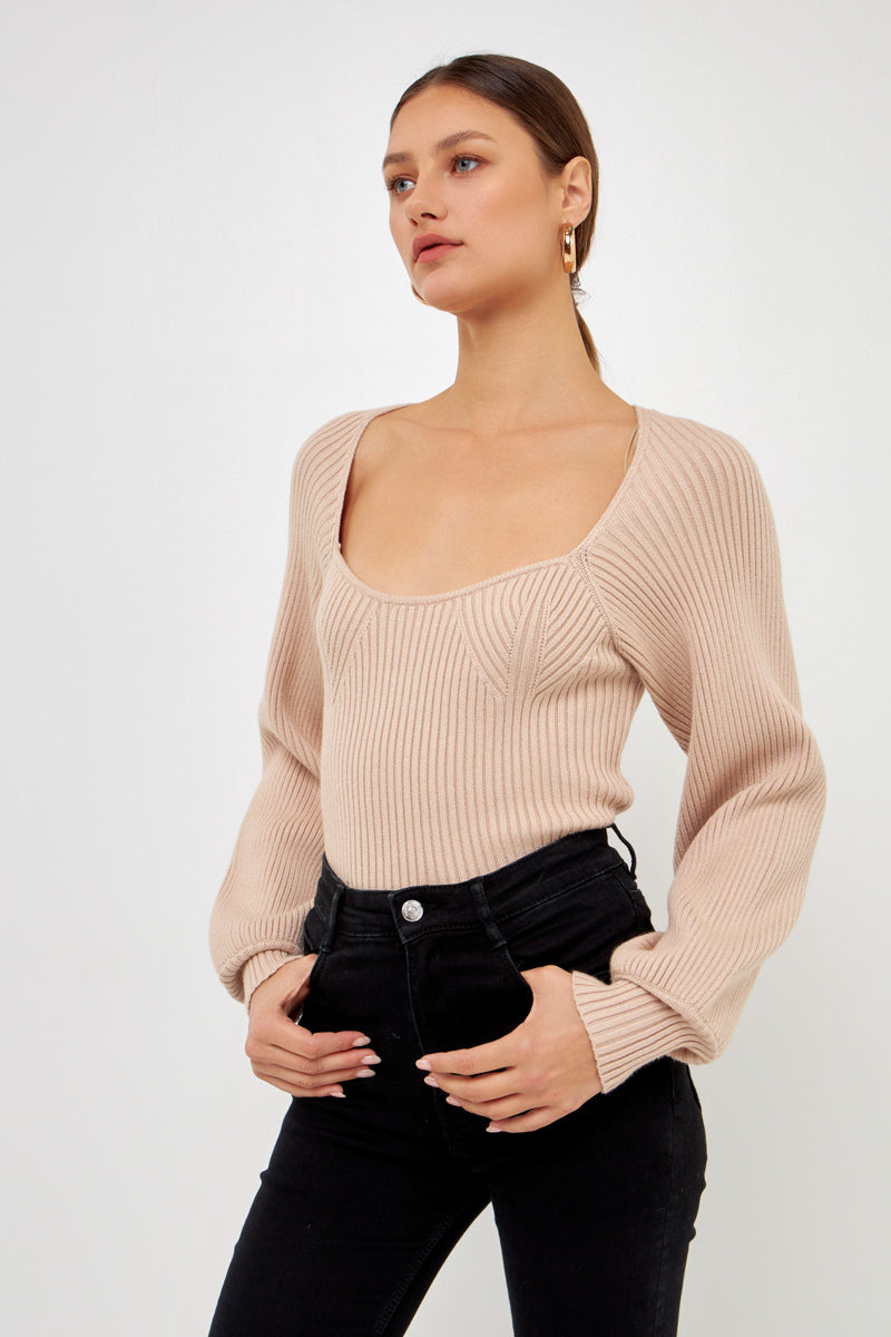 Knitted top in beige featuring square neckline, ribbed detailing, balloon sleeves.  Front close view.