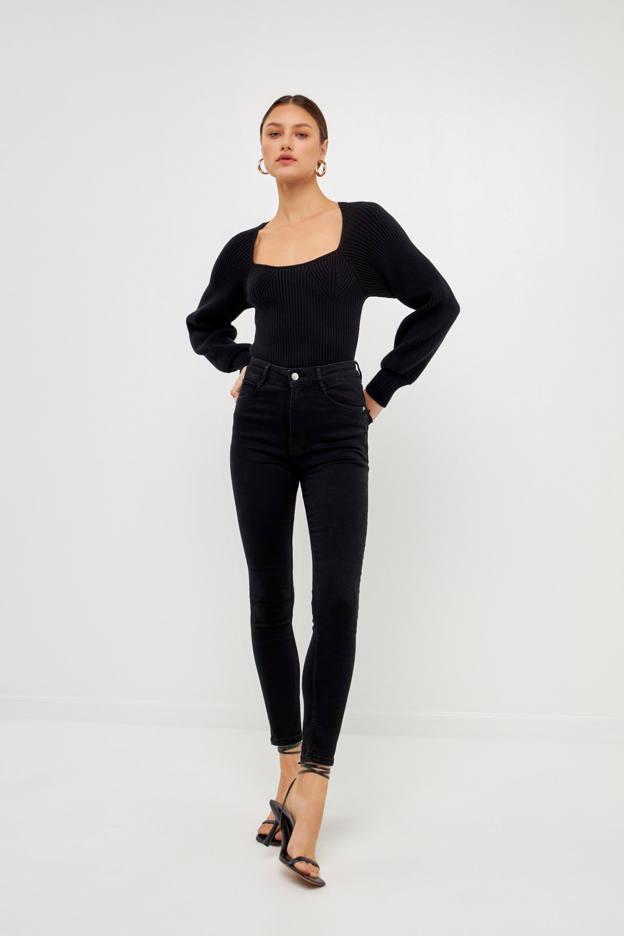 Knitted top in black featuring square neckline, ribbed detailing, balloon sleeves.  Front full view.