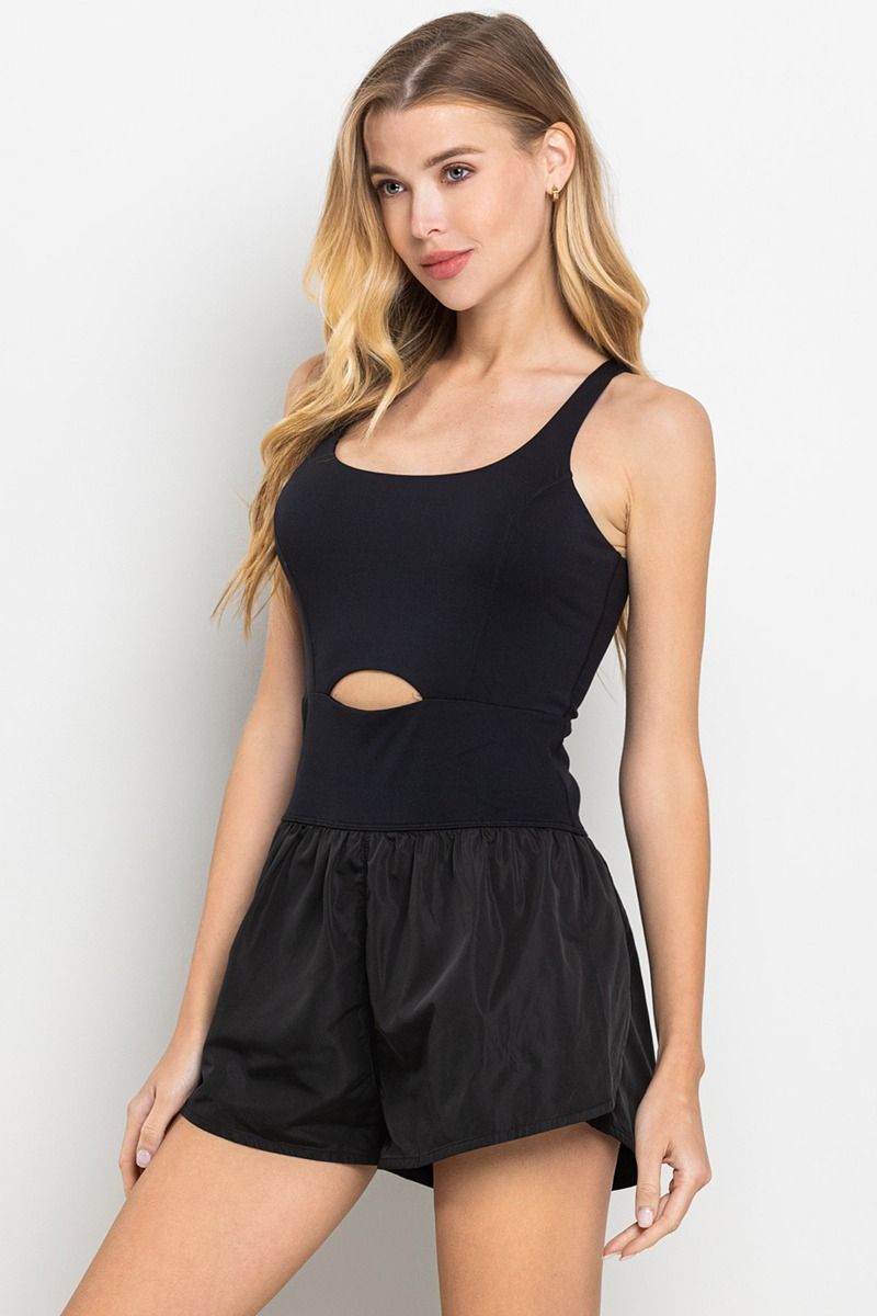 A sleeveless athletic romper in black with a small center cut out, and an elastic waistband - side view