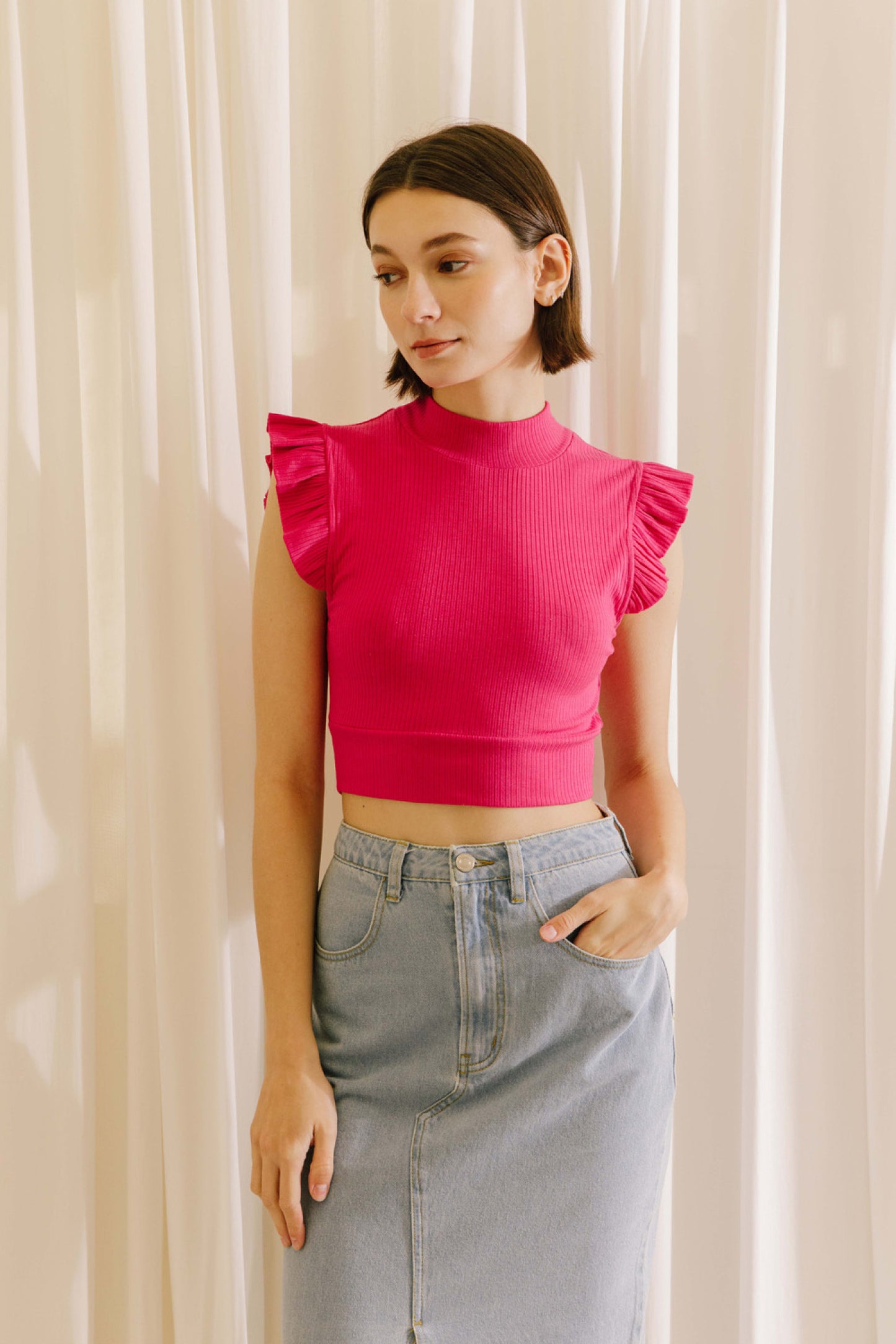 Ribbed knit mock neck crop top in fuchsia featuring ruffle sleeves.  Close front view.