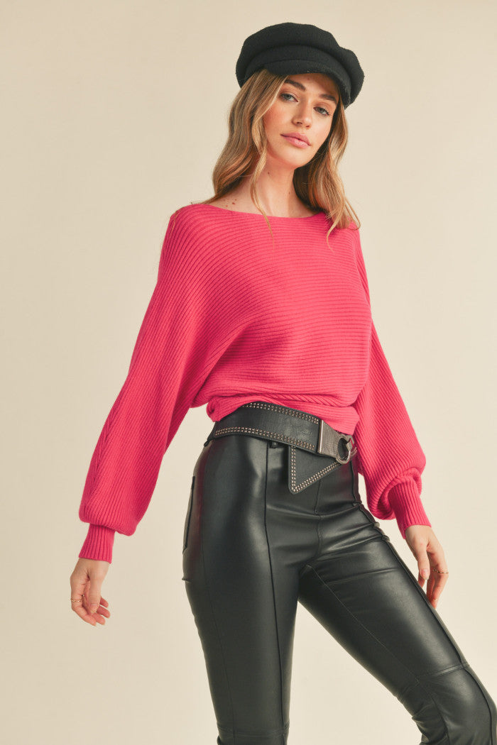 Ribbed sweater in pink with long dolman-style sleeves, boat neckline, relaxed bodice, and a fitted waist.  Front view.