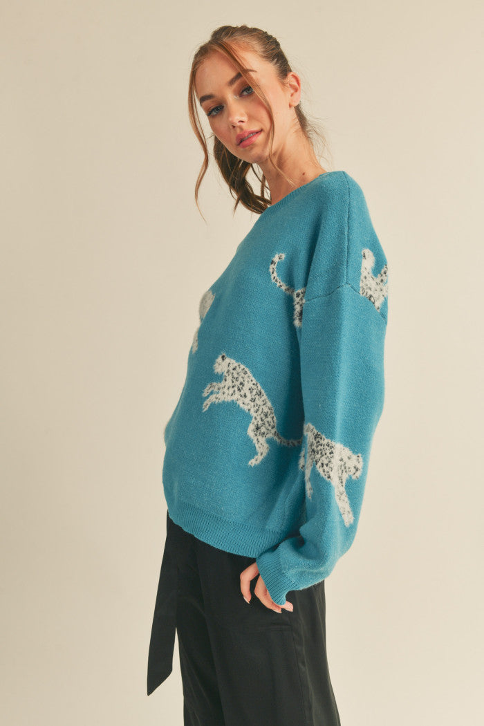 Leopard knit sweater in teal.  Black & white mohair leopard. Ribbed crewneck. Drop shoulder long sleeves. Relaxed fit pullover.  Side view.