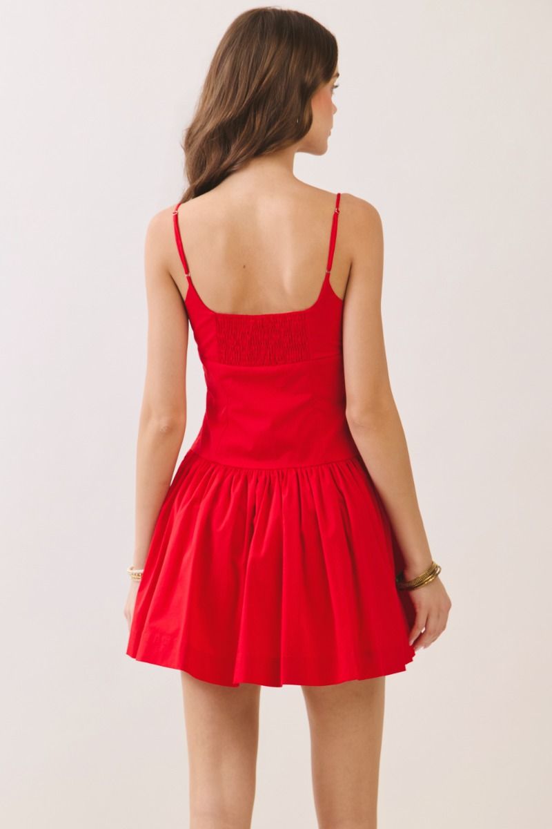 Red dress worn by a person on a plain background, back view.
